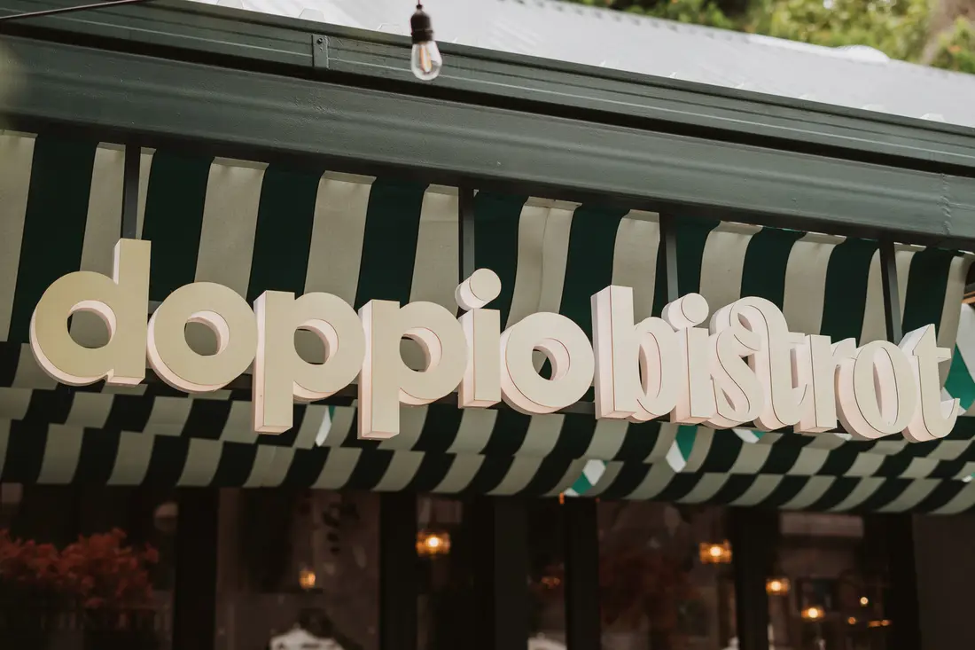 The green and white striped awning of Doppio Bistrot