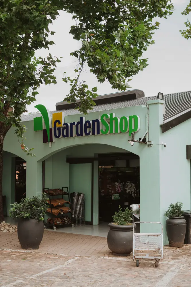 The GardenShop front in mint green, with potted plants