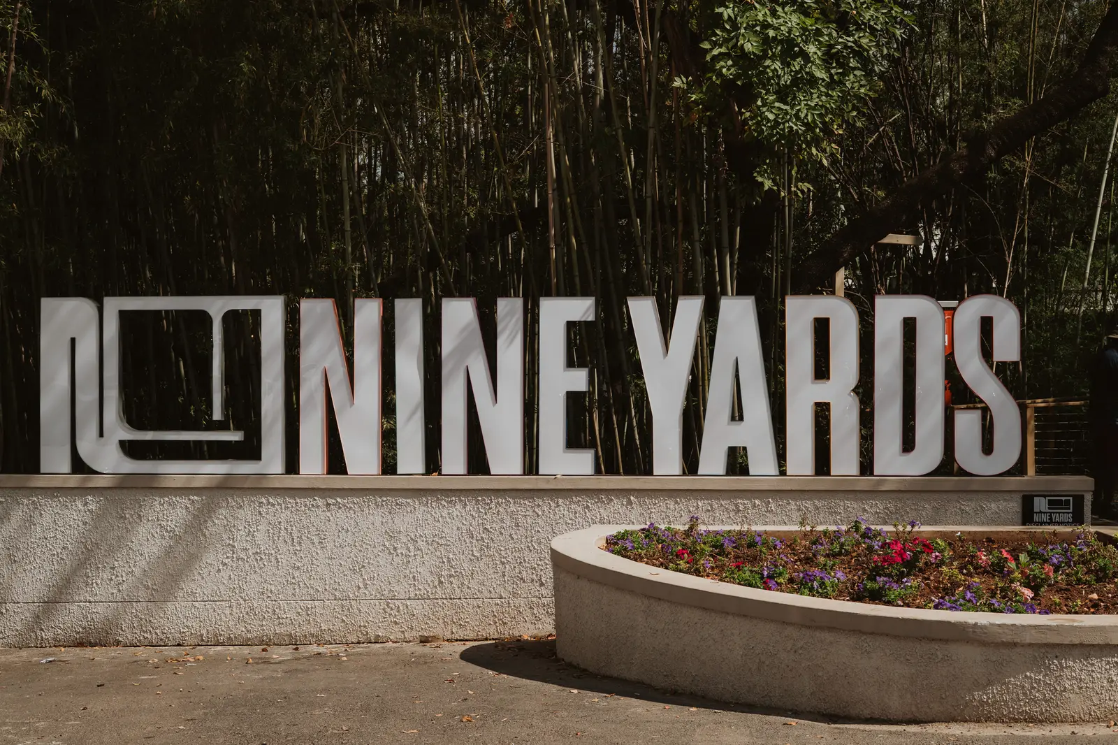 The Nine Yards sign standing over a planter