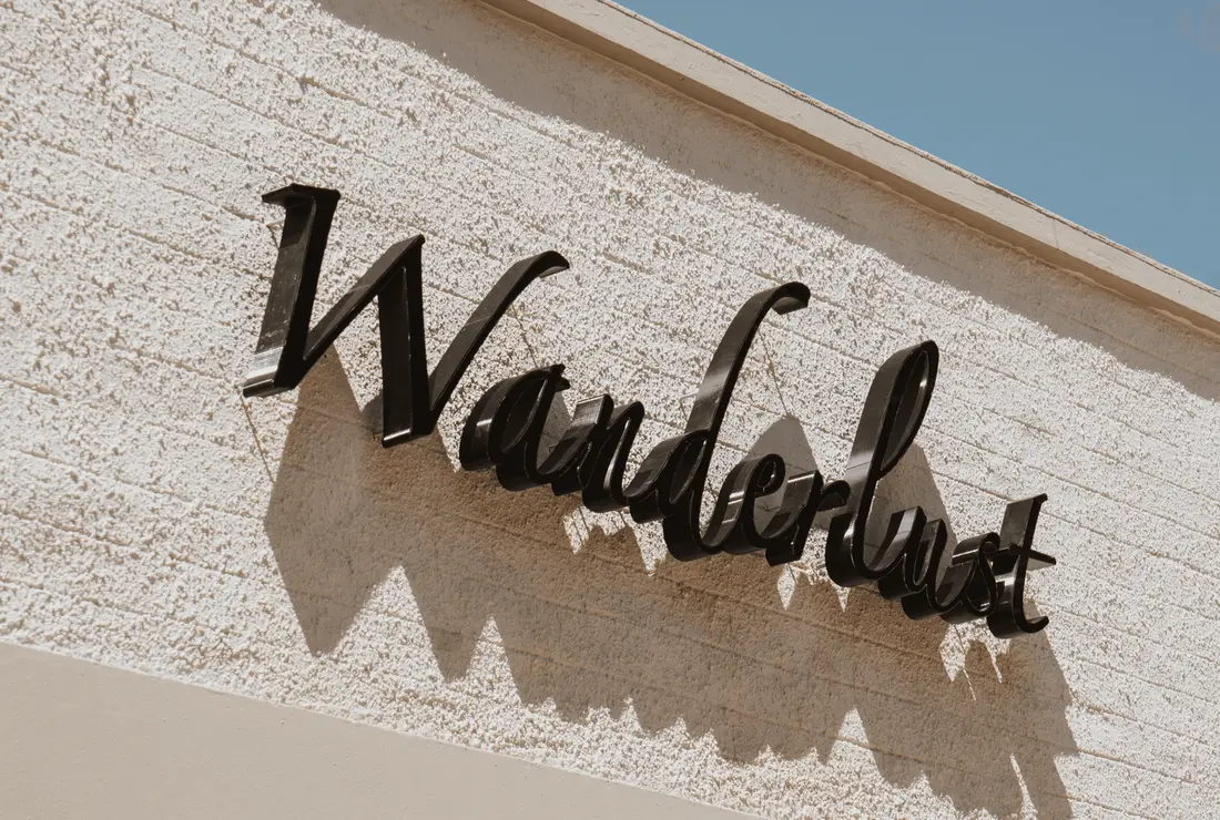 The Wanderlust sign in black script on a stucco wall